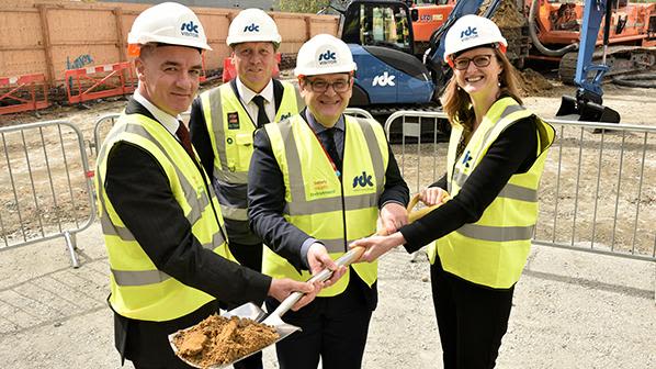 Four people in high-vis and hard hats at ground-breaking ceremony