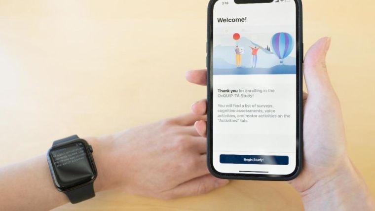 Person wearing Apple watch and holding phone used for home monitoring of Parkinson's symptoms.