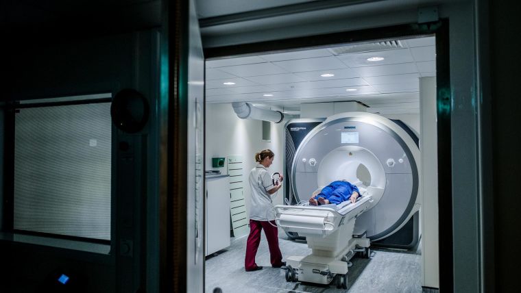 Person going into MRI scanner with radiographer standing by