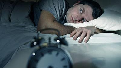 Man lying awake next to alarm clock