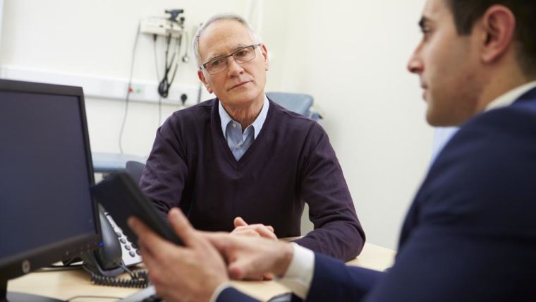 Consultation between male GP and patient looking at test results