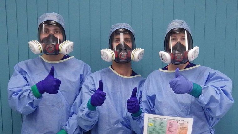 Intubation team of two men and a woman in full personal protective equipment